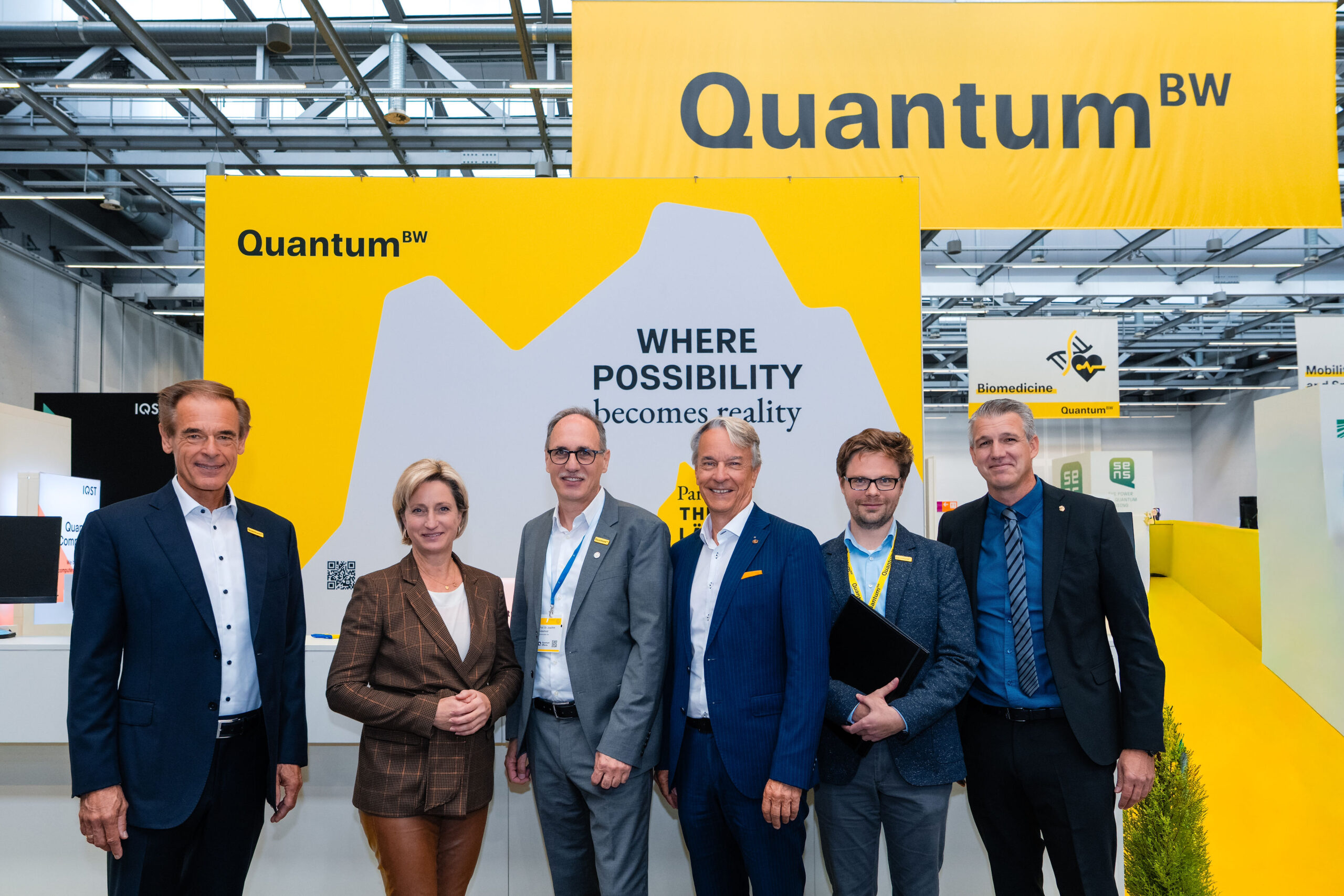QuantumBW Messestand auf der Quantum-Effects 2025 vor dem Vertretende aus Politik, Industrie und Forschung stehen.